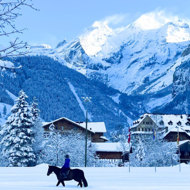 WINTERWERKE 2024 - 1. Die Frutigerin Erika Bärtschi fotografierte ein Pferd mit Reiterin, das vor der Blümlisalp durch den Schnee stapft.